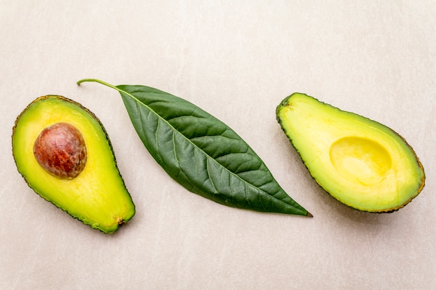 Avocado, cut in half, with a bone and avocado leaf