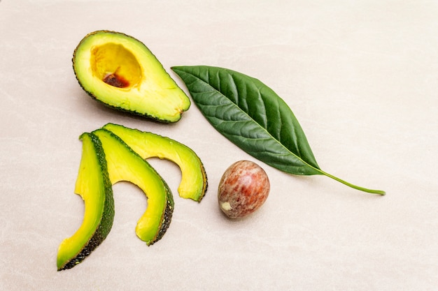 Avocado, cut in half with bone, avocado slices, and avocado leaf with soy sauce