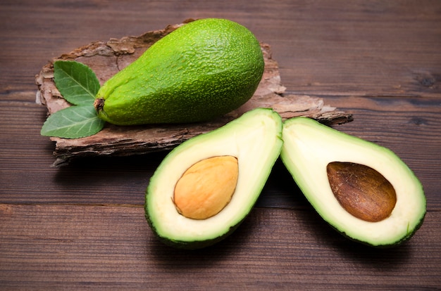 Avocado cutaway fruit halves on wooden background