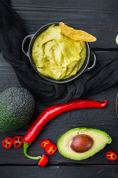 Avocado dip or guacamole in bowl, on black wooden table, top view or flat lay