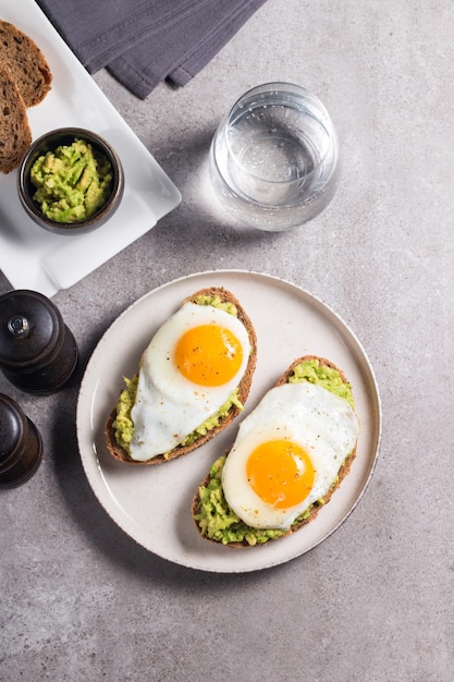 Avocado egg sandwich with a glass of water. Healthy light breakfast concept. Whole grain toasts with