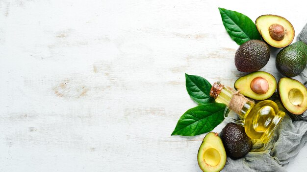 Avocado- en avocado-olie op een witte houten ondergrond Rustieke stijl Bovenaanzicht Vrije ruimte voor uw tekst