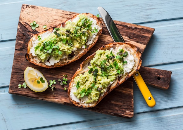 Avocado en labne toast met microgroenten op een snijplank bovenaanzicht Goede vetten gezond eten