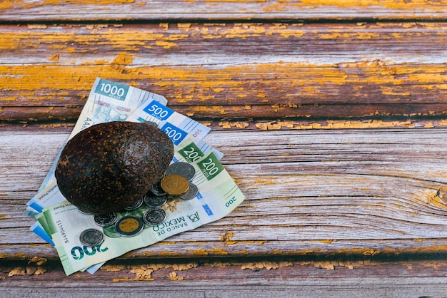 Avocado en Mexicaanse bankbiljetten op houten tafel Concept van stijgende kosten van avocadoconsumptie
