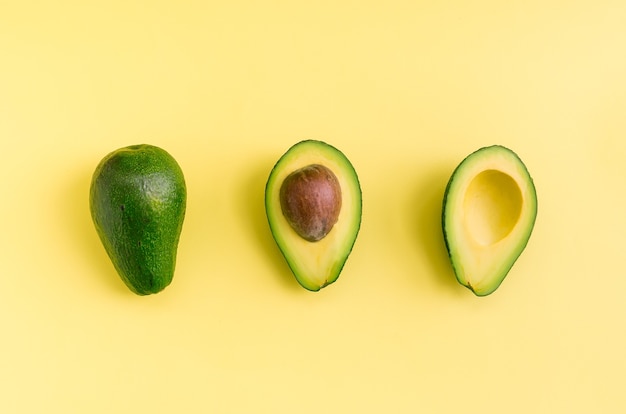 Avocado flat lay on yellow background. Simple and minimal concept. Organic healthy food. Top view.