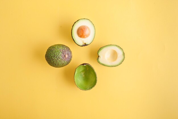 avocado geheel en half op gele achtergrond