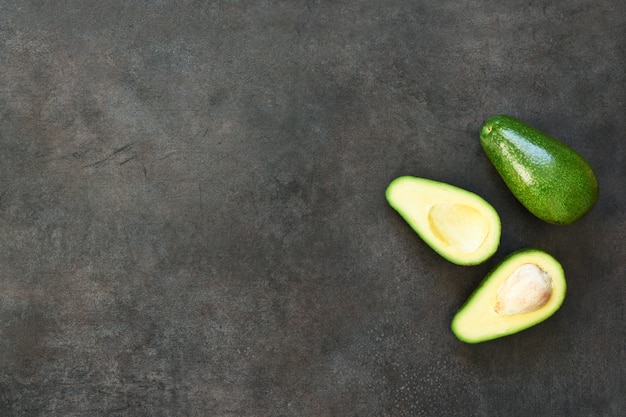 Avocado gesneden. Verse avocado op een zwarte steenachtergrond.