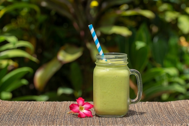 Avocado green shake or smoothie on the table, close up. Breakfast in island Bali, Indonesia. The concept of healthy eating.