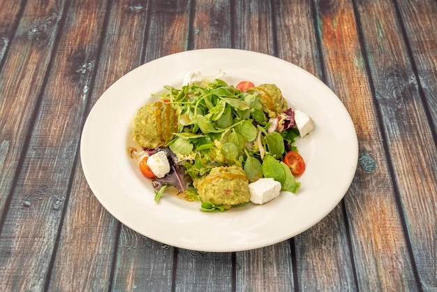 Avocado guacamole salade sla spruiten veldsla fetakaas kerstomaatjes en een ronde witte plaat