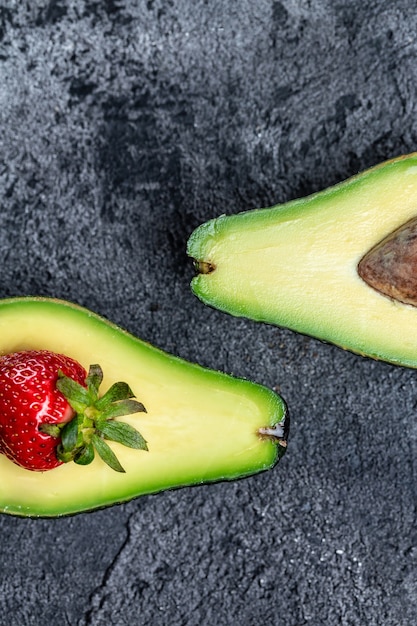 Avocado halveren en in plakjes snijden met aardbei. Detox-concept. verticaal beeld. bovenaanzicht.