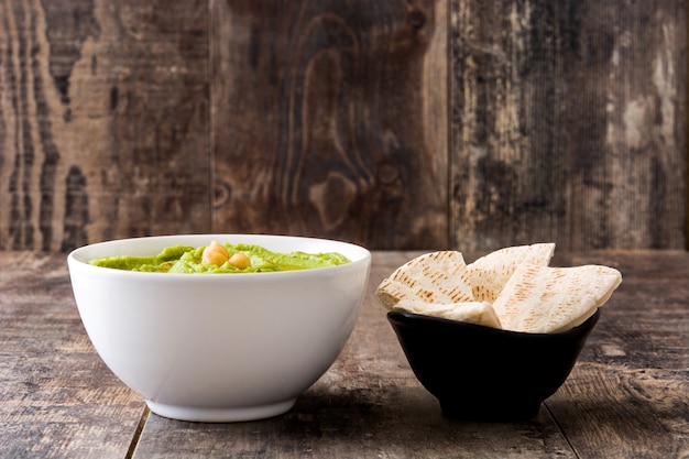 Avocado hummus in bowl with pita bread on wooden table