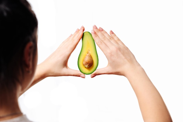 avocado in een vrouwelijke hand op een witte achtergrond