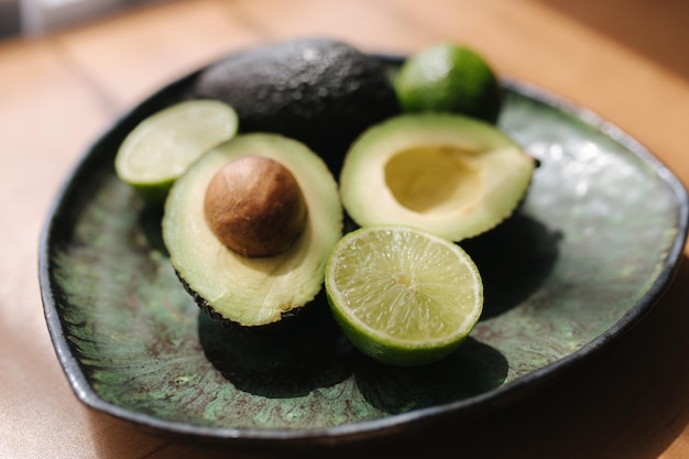 Avocado and lime halves on green plate Vegetarian food concept