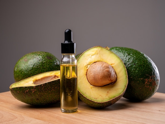 Avocado oil with avocado fruit on wooden table. Avocado is a highly nutritious fruit.