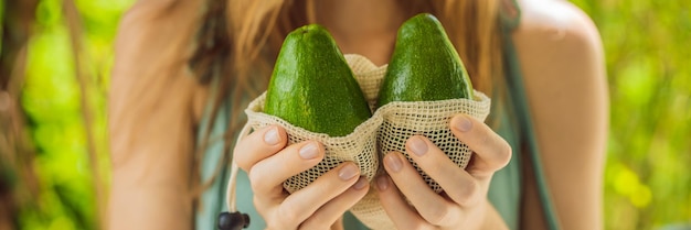 Avocado in a reusable bag in the hands of a young woman zero waste concept banner long format