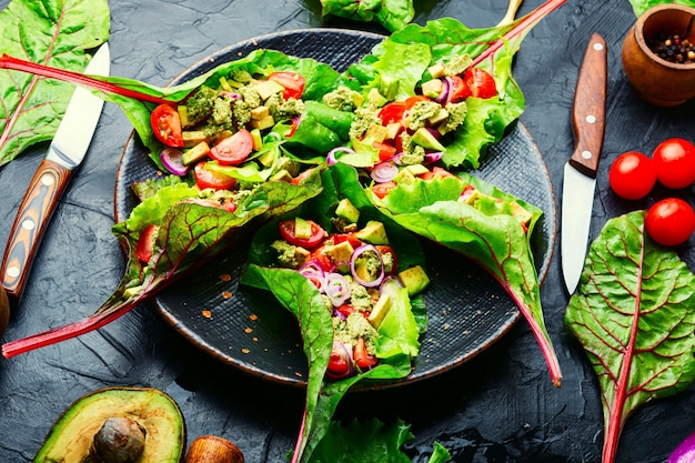 Avocado salad, tomato with garlic sauce in chard leaves.Summer vitamin salad in plate