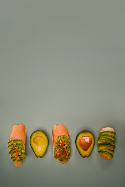 Foto avocado sandwich en halve avocado op groene achtergrond. ruimte kopiëren.