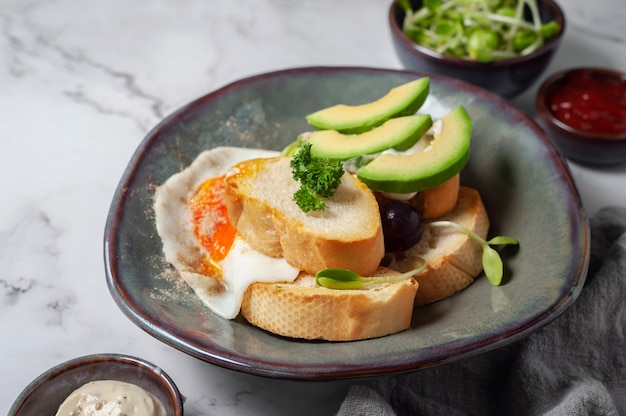 Photo avocado and sandwich with fried egg. tree sliced avocado and fried egg on toasted bread for breakfast.