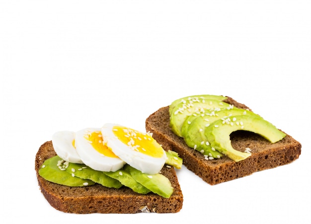 Avocado slices and eggs on rye bread with sesame