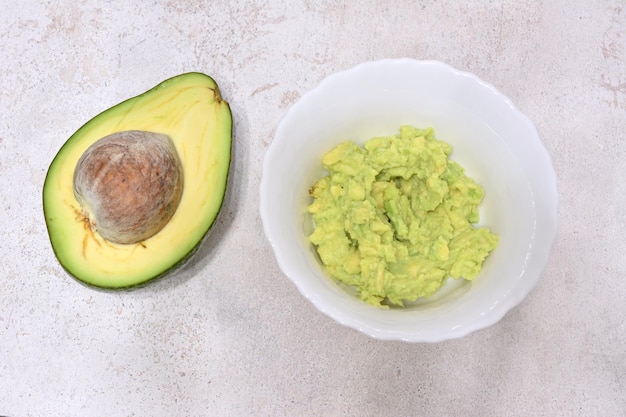 Avocado and smashed avocado in white bowl isolated closeup