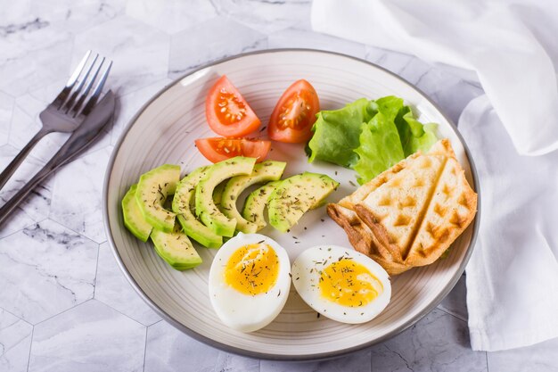 Avocado soft boiled egg tomatoes lettuce and toast on a plate Healthy food