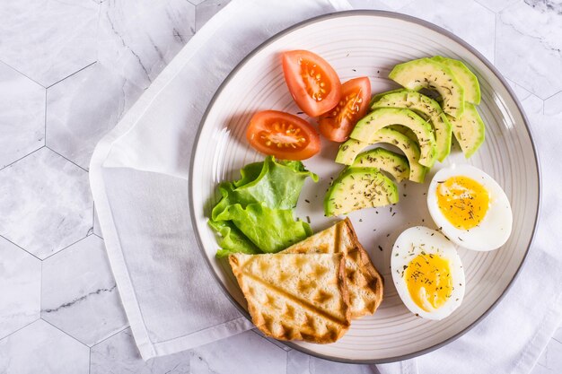 Avocado soft boiled egg tomatoes and toast on a plate Homemade breakfast Top view Closeup