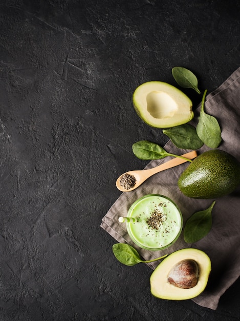 Avocado and spinach smoothie in glass with chia seeds over black background