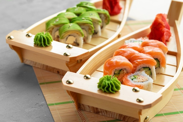 Avocado sushi roll and roll with salmon served on wooden plates