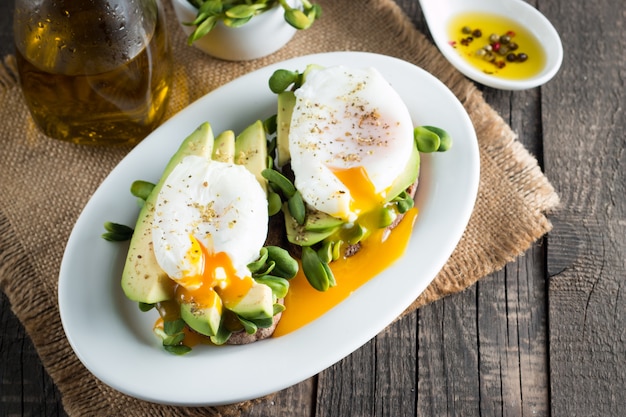 Avocado toast with poacehd egg on wooden background. 