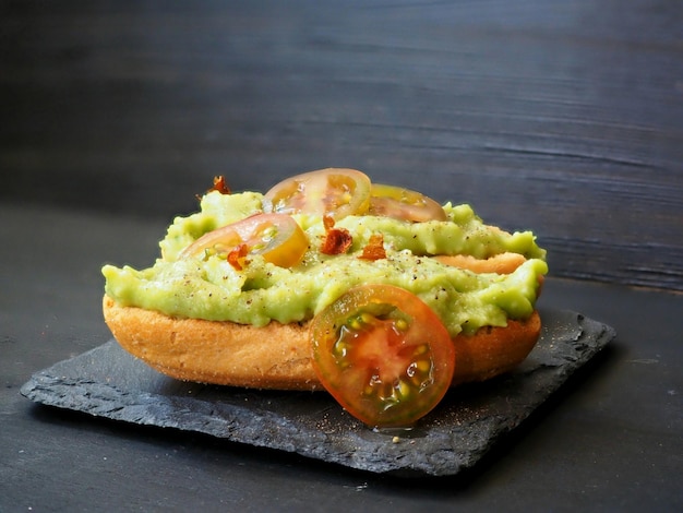 Avocado toast with tomatoes on a stone board isolated on black background Breakfast concept