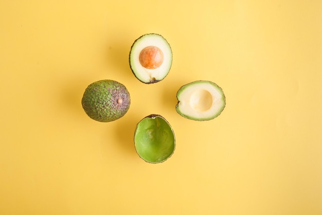 avocado whole and half on yellow background