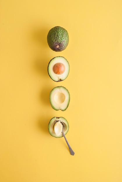 avocado whole and half on yellow background