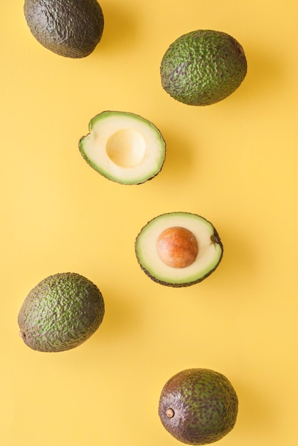 avocado whole and half on yellow background