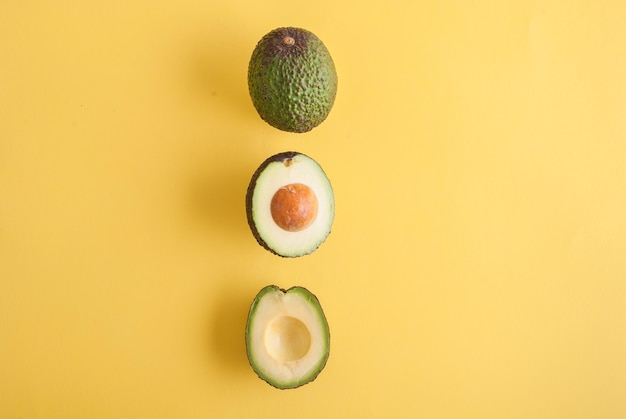 avocado whole and half on yellow background