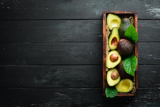 Avocado with leaves in the box Rustic style Top view Free space for your text