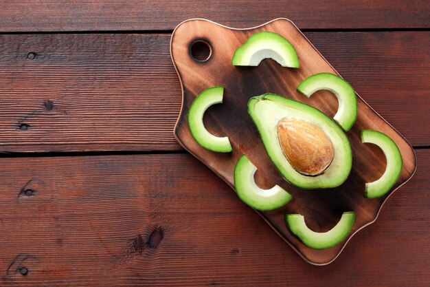 Авокадо на деревянной доске Нарезанный авокадо на деревянном фоне Вегетарианская еда Копией пространства