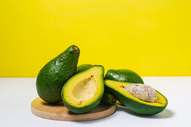 Avocado on yellow white background cut avocados in wood plate\
fresh green avocado food concept