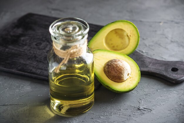 Avocadofruit en olie in glazen fles