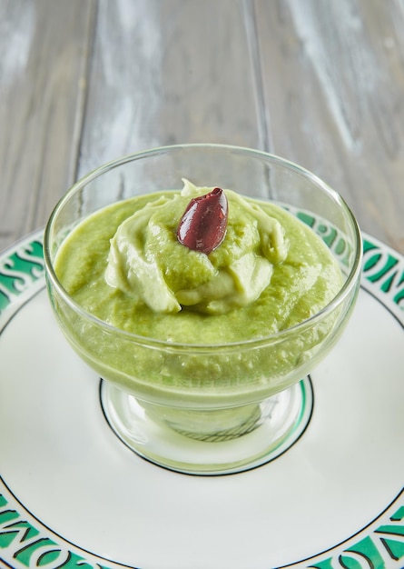 Avocadomousse met olijven in doorzichtige glazen beker op bord