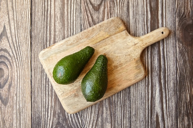 Avocados on cutting board on wooden table