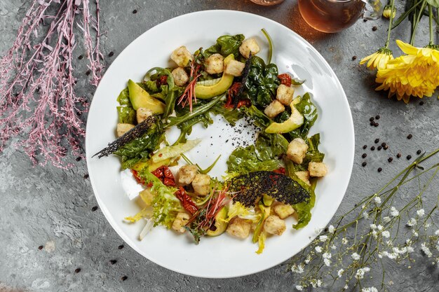 Avocadosalade met babyspinazie en granaatappel op een zwart bord op een leisteen of betonnen achtergro...