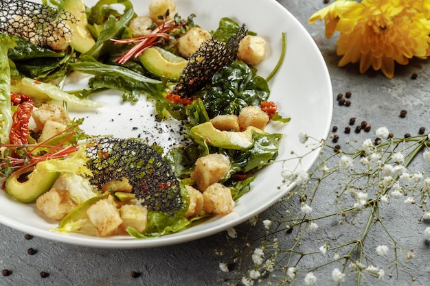 Avocadosalade met babyspinazie en granaatappel op een zwarte plaat op een leisteen of betonnen ondergrond Bovenaanzicht met kopieerruimte