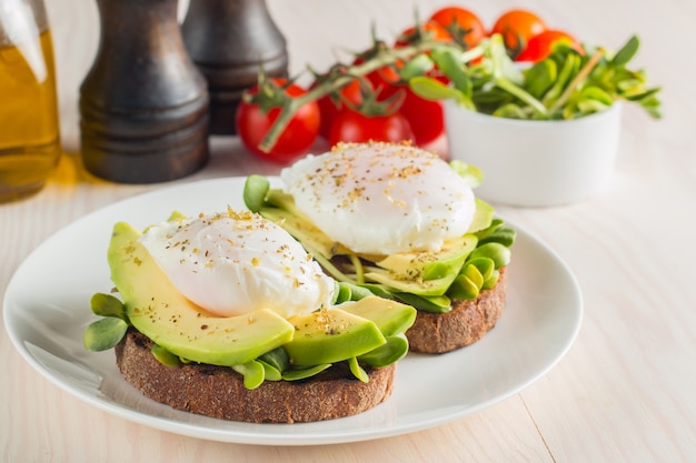 Avocadotoost, kersentomaat en gestroopte eieren op houten achtergrond.