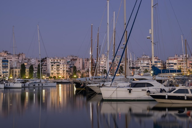 Avond kuststad, boten en jachten in de haven, reflectie op het water van hen, Griekenland