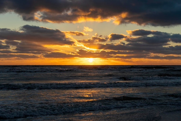 Avond landschap van zeewater golven verpletterend op zandstrand bij zonsondergang
