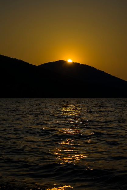 Avond zonsondergang achter de berg op een groot meer romantisch uitzicht op de zonsondergang op het meer tussen de...