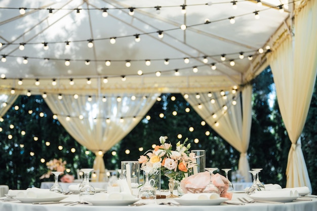 Avonddecoratie van een huwelijksfeest Tafels voor gasten met een slinger en lampen