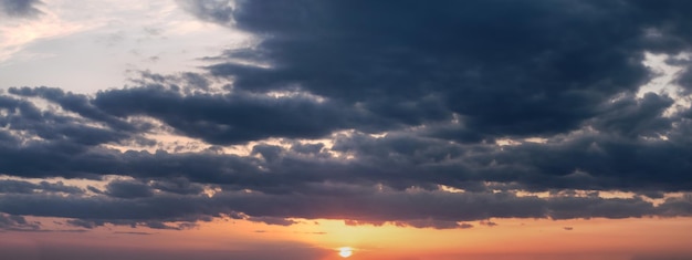 Avondluchtpanorama met geeloranje zonsondergang en sombere wolken