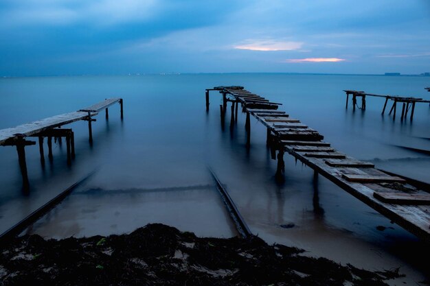avondzeegezicht drie oude houten bruggen die naar de open zee leiden donkerblauwe lucht