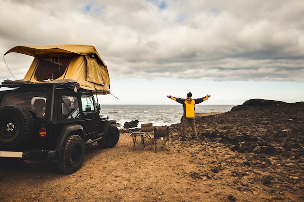 Avonturier man in reis reizen met off-road auto en daktent om te genieten van vrijheid en ontdekkingsreiziger concept ontdek de wereld die leeft in de buurt van de kracht van de natuur oceaan kust huis uitzicht